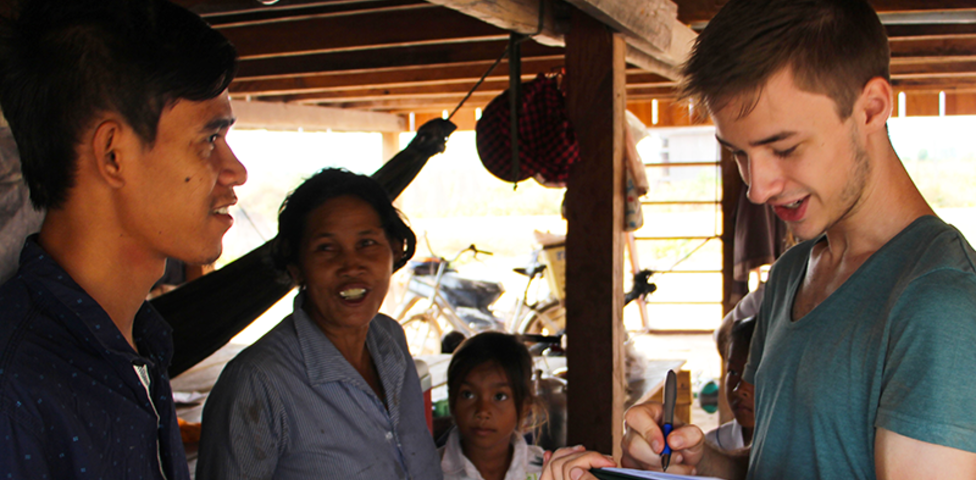 Europäischer junger Mann mit südostasiatischer Familie in Holzhaus mit Klemmbrett in der Hand